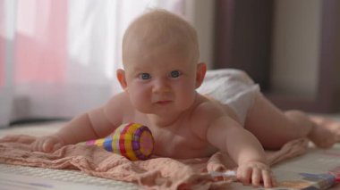 Yerde yumuşak bir yatakta yatan 4 aylık bebeğiniz kutlu olsun. Bebek bakımı, bebek sağlığı, erken gelişim, çocuk sevgisi, aile sevgisi ve ebeveynlik yaşam tarzı kavramı.