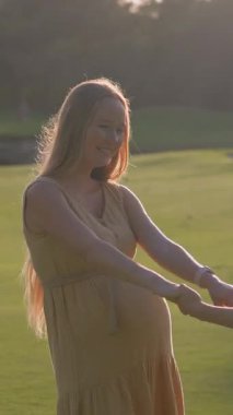 Hamile anne ve büyük oğlu gün batımında yemyeşil bir alanda neşeli anların tadını çıkarıyorlar. Güzel annelik bağı, çocukluk sevinci ve sevgi dolu aile zamanı. Açık havada mutluluk