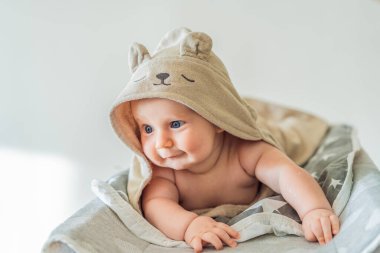 Bebek, evde banyo yaptıktan sonra yumuşak bir havluya sarılı bir şekilde üzerini değiştiriyor. Temiz, sakin ve rahat bir bebek bakımı ve güvenliği anı. Bebek hijyeni, günlük rutin ve nazik ebeveynlik kavramı.