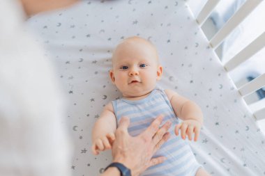 Baba bebeğini nazikçe evdeki bir beşiğe yerleştiriyor, sakin ve güvenli bir uyku zamanı yaratıyor. Babalığı önemseme sahnesi güven ve sıcaklıkla dolu. Ebeveynlik, bebek uykusu ve aile bağları.