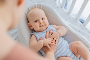 Anne beşikte nazikçe oturuyor ve sıcak bir koza yuvasında bebeğini okşuyor. Evde şefkatli samimi bir ilgi ve güven anı. Annelik, bebek uykusu ve duygusal bağ konsepti..