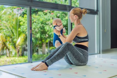Anne, bebeğini kucağında tutarken spor yapıyor. Spor ve çocuk bakımını birleştiriyor. Dengeyi, gücü ve sevgiyi gösteren gerçek bir yaşam tarzı. Doğum sonrası sağlık, sağlıklı annelik ve...