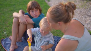 Genç anne, oğluyla yemyeşil bir parkta kaliteli zaman geçiriyor. Doğanın, kahkahaların ve neşeli aile bağlarının tadını çıkarıyor.