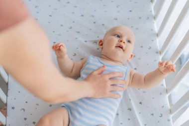 Anne beşikte oturup bebeğini nazikçe okşuyor evdeki rahat bir yatakta yatıyor. Sevgi, güven ve sükunetle dolu sıcak ve samimi bir an. Annelik, bebek rahatlığı ve duygusal bağ konsepti..