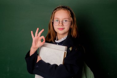 Okula dönelim. Tahtada kitap tutan bir çocuk. Liseli kız. Okul çocuğu. İlkokul öğrencisinin portresi. Mutlu liseli kız. Okul çocuğu ya da anaokulu öğrencisi.