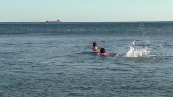 Dos niños vestidos con mangas inflables nadan en mar abierto — Vídeos de Stock