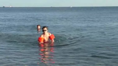 Gözlük ve turuncu şişme kollu küçük çocuk üzerinden deniz gidiş dışarı da kamera tarafa taş atma