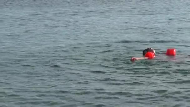 Chico divertido vestido con brazalete naranja se está bañando y buceando en el Mar Negro — Vídeo de stock