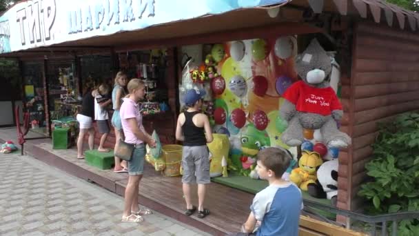 Жінка і дві хлопчики стоячи біля розваг із кількох кольорові повітряних кулях — стокове відео