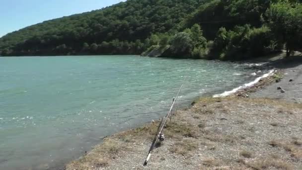 Rybářský prut je na břehu Bright Blue Lake poblíž hor — Stock video
