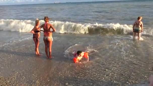 Küçük çocuk çakıl plaj dalgalar deniz içinde sıcak güneşli bir günde tarama — Stok video