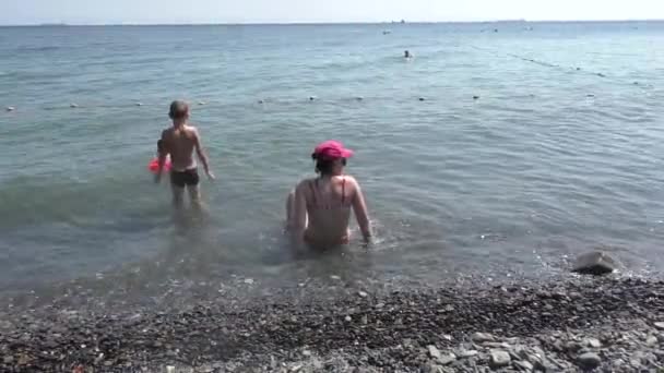 Η οικογένεια είναι χαλαρώνοντας στην παραλία της θάλασσας σε καυτό ηλιόλουστη μέρα Βίντεο Αρχείου
