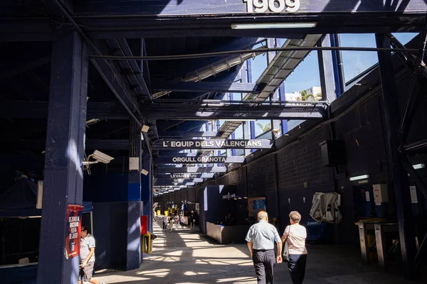 Tutkulu Levante UD destekçileri güneşli bir maç gününde Estadio Ciudad de Valencia tribünlerinde kutlama yapıyorlar. Kalabalık enerji dolu, takım eşarpları sallıyor ve etrafında uçan konfetiler var.