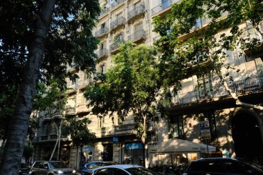 Detaylı taş işçiliği olan zarif tarihi binalar ve açık mavi gökyüzüne karşı güneş ışığıyla yıkanmış dekoratif bir kule. Düşük bir açıdan yakalanan bu resim klasik Avrupa mimarisini vurgular