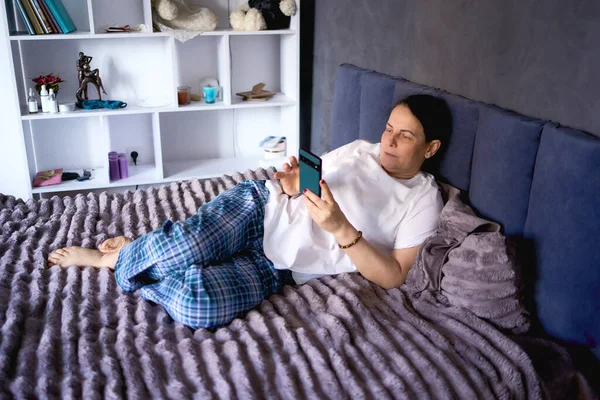    Son sınıf öğrencisi kadın yatakta telefonla konuşuyor.                            