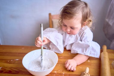  Bebek mutfakta zencefilli kurabiye evi için krema pişiriyor.                     