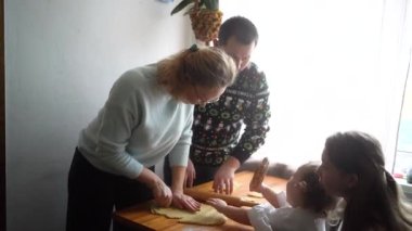 İki kızı olan bir aile, bir genç ve bir bebek, mutfakta birlikte kurabiye pişiriyorlar.