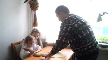 İki kızı olan bir aile, bir genç ve bir bebek, mutfakta birlikte kurabiye pişiriyorlar.