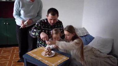 Çocukları olan bir aile zencefilli kurabiyelerden bir Noel ağacı yapar ve onu beyaz krema ve mavi kar taneleriyle süsler.