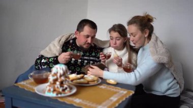 Çocukları olan bir aile zencefilli kurabiyelerden bir Noel ağacı yapar ve onu beyaz krema ve mavi kar taneleriyle süsler.