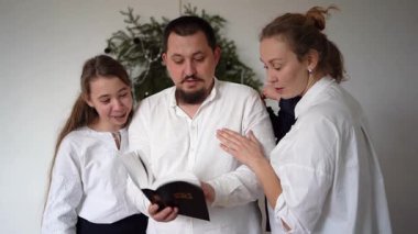Noel kutlaması sırasında İncil okuyan çocuklu bir aile.