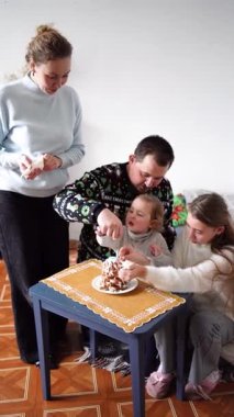 Çocukları olan bir aile zencefilli kurabiyelerden bir Noel ağacı yapar ve onu beyaz krema ve mavi kar taneleriyle süsler.
