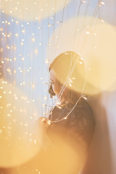 Девочка-подросток в платье в окружении золотых рождественских огней