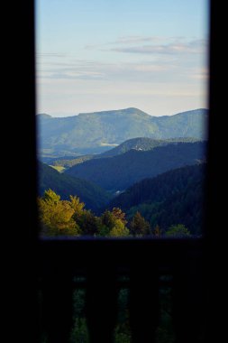 Otel odasının kırsal ahşap penceresinden dağ manzarası