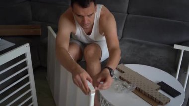 Yeni baba, yeni bebeği için parlak, basit bir odada beşik yapacak.