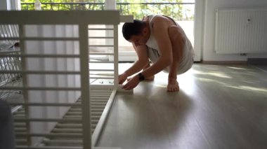 Yeni baba, yeni bebeği için parlak, basit bir odada beşik yapacak.