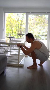 Yeni baba, yeni bebeği için parlak, basit bir odada beşik yapacak.