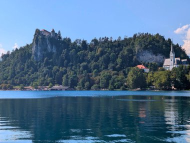 Ada kilisesi ve arka planda dağlarla birlikte panoramik göl manzarası.