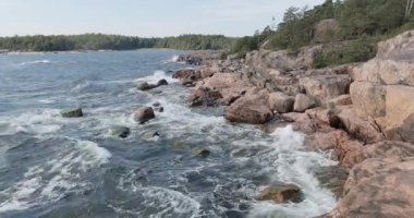 Pirttisaari Doğa Koruma Alanı 'nda kayalık sahile vuran dalgaların hava görüntüsü, güneşli yaz havasında, Pirttisaari, Porvoo, Finlandiya.