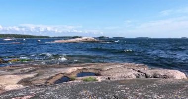 Pirttisaari doğa kayalık deniz manzarası güneşli yaz havasında kıyıya vuran dalgalarla gökyüzünde bulutlar, Pirttisaari, Porvoo, Finlandiya. 