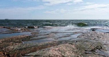 Pirttisaari doğa kayalık deniz manzarası güneşli yaz havasında kıyıya vuran dalgalarla gökyüzünde bulutlar, Pirttisaari, Porvoo, Finlandiya. 