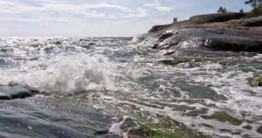 Pirttisaari doğa kayalık deniz manzarası güneşli yaz havasında kıyıya vuran dalgalarla gökyüzünde bulutlar, Pirttisaari, Porvoo, Finlandiya. 