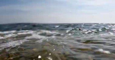 Güneşli yaz havasında kayalık kıyıya vuran dalgaların yakın görüntüsü gökyüzünde bulutlar, Pirttisaari doğa rezervi, Porvoo, Finlandiya. 