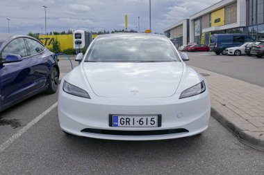 Laajalahti, Finlandiya - 19 Ağustos. 2025: Tesla Model 3 alışveriş merkezinin park yerine park edilmiş elektrikli araba elektrik yükleme istasyonu.