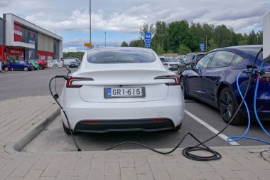Laajalahti, Finlandiya - 19 Ağustos. 2025: Tesla Model 3 alışveriş merkezinin park yerine park edilmiş elektrikli araba elektrik yükleme istasyonu.