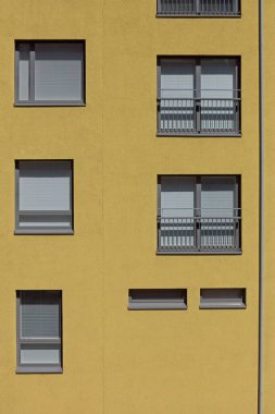 Güneşli yaz mevsiminde sarı bir bina duvarındaki standart pencere ve camlar, Konepaja, Helsinki, Finlandiya.