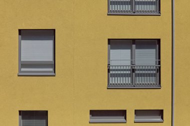 Güneşli yaz mevsiminde sarı bir bina duvarındaki standart pencere ve camlar, Konepaja, Helsinki, Finlandiya.