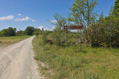 Güneşli yaz mevsiminde Uku 'nun toprak yolu boyunca uzanan Aljava Ukukivi' ye giden yol tabelası, Muhu, Estonya.