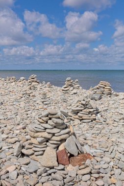 Bir yaz günü gökyüzünde bulutlar, Tagaranna, Saaremaa, Estonya ve Estonya 'da deniz kıyısında bir çakıl taşı plajına inşa edilmiş insan yapımı birkaç cairns..