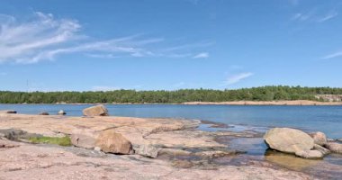 Pürüzsüz granit kayalık kıyıları ve güneşli yaz havasında yoğun bir kozalaklı orman hattının yer aldığı ada kıyıları, Pirttisaari, Finlandiya, Avrupa.