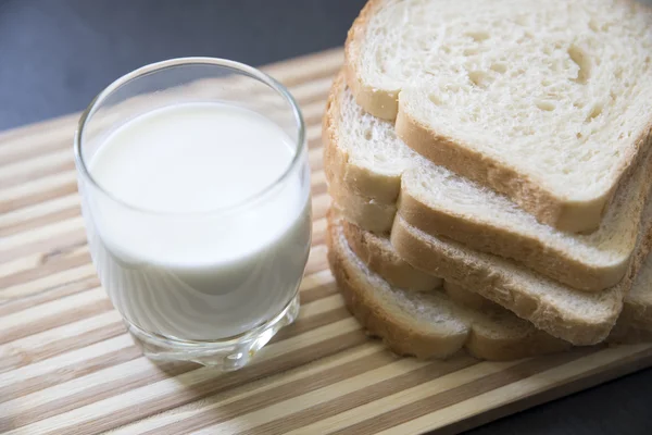Κομμάτια ψωμί και ένα ποτήρι γάλα σε βάση — Φωτογραφία Αρχείου
