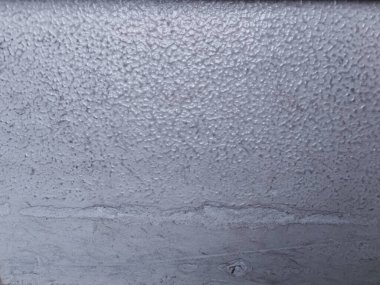 Close-up of rough cement wall texture with stippled surface and horizontal seam. Ideal for abstract backgrounds, architectural design, or material reference.