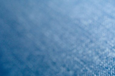 Soyut mavi yüzeye yakın çekim, ince yükseltilmiş doku ve parlak röfleler. Arkaplan, tasarım ögeleri veya malzeme referansı için ideal.