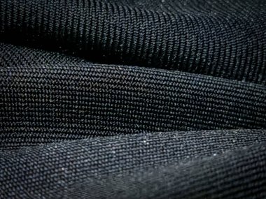İnce desenli ve kıvrımlı siyah örülmüş kumaş. Soyut arka planlar, tekstil tasarımı, moda veya maddi referanslar için ideal.