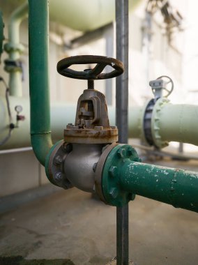 Endüstriyel su boru vanasına yakın çekim, paslanma ve yıpranmayı gösteriyor. Fabrika, mühendislik ve bakım temaları için ideal.