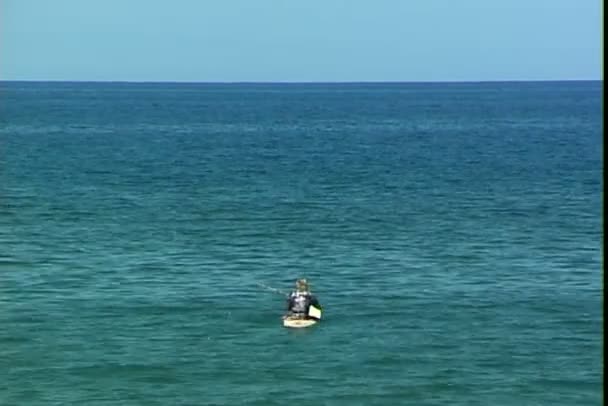 Rybář na surfovací prkno v oceánu — Stock video